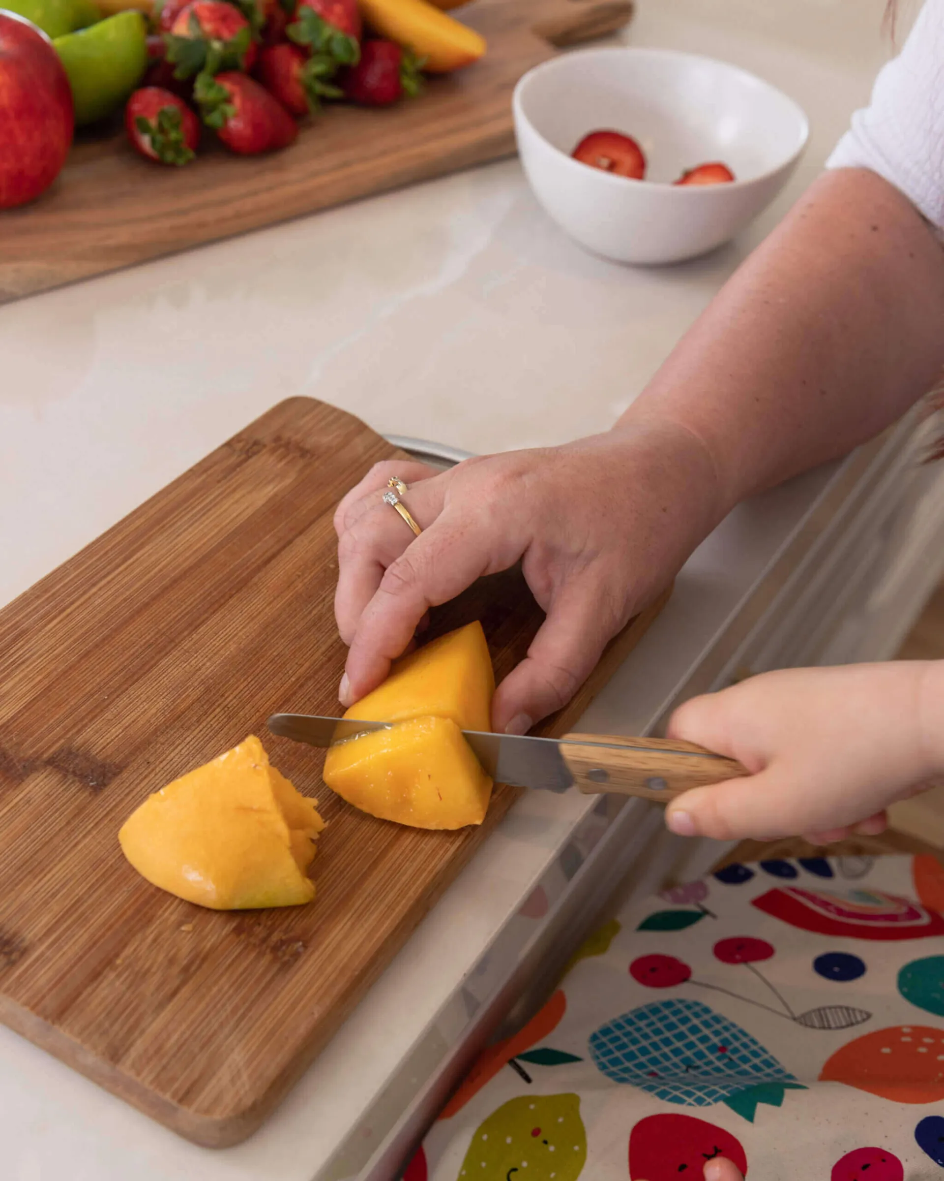 Wooden KiddiKutter slicing fruit on a chopping board