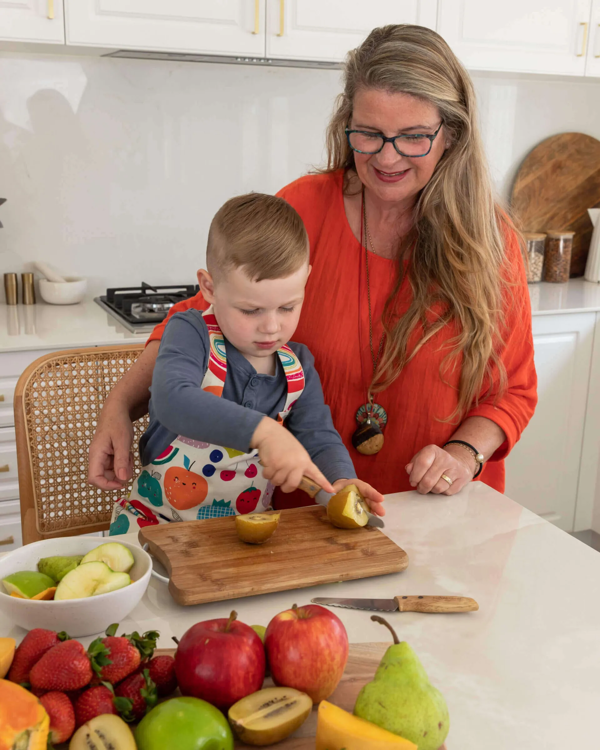 Child preparing food with a parent using a wooden KiddiKutter