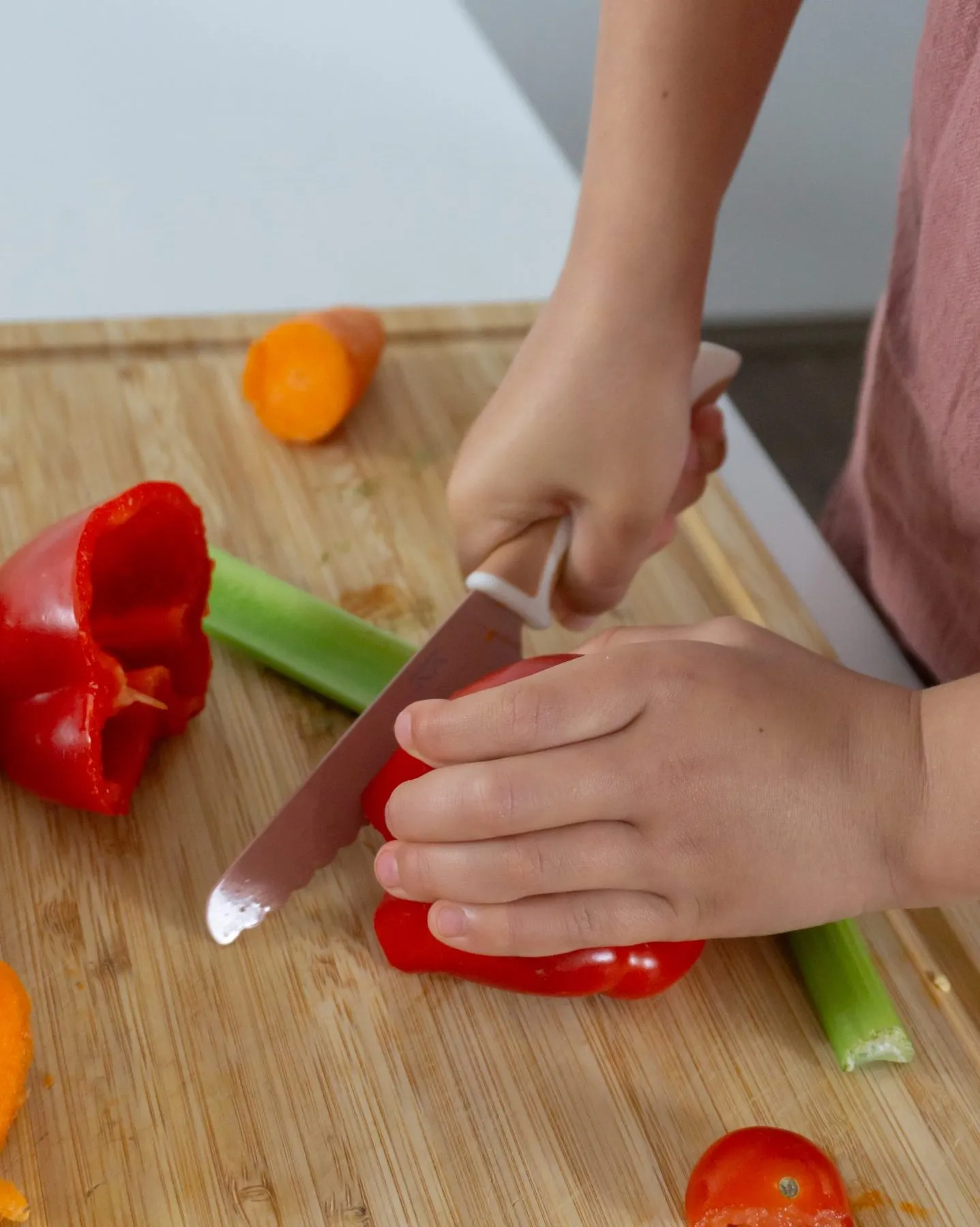 Child cutting red capsicum with a KiddiKutter knife