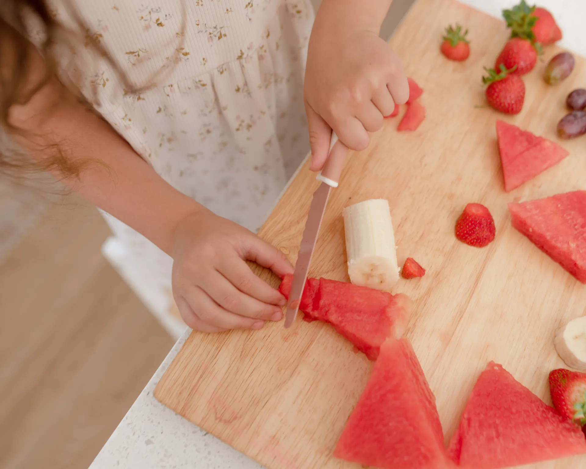 Child slicing watermelon with a Dusky Rose KiddiKutter