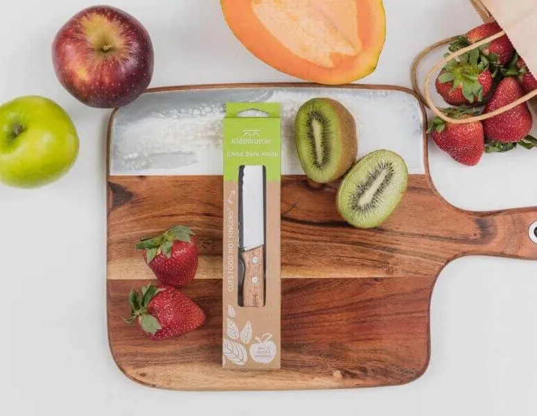 KiddiKutter knife on a board with sliced kiwi fruit and strawberries