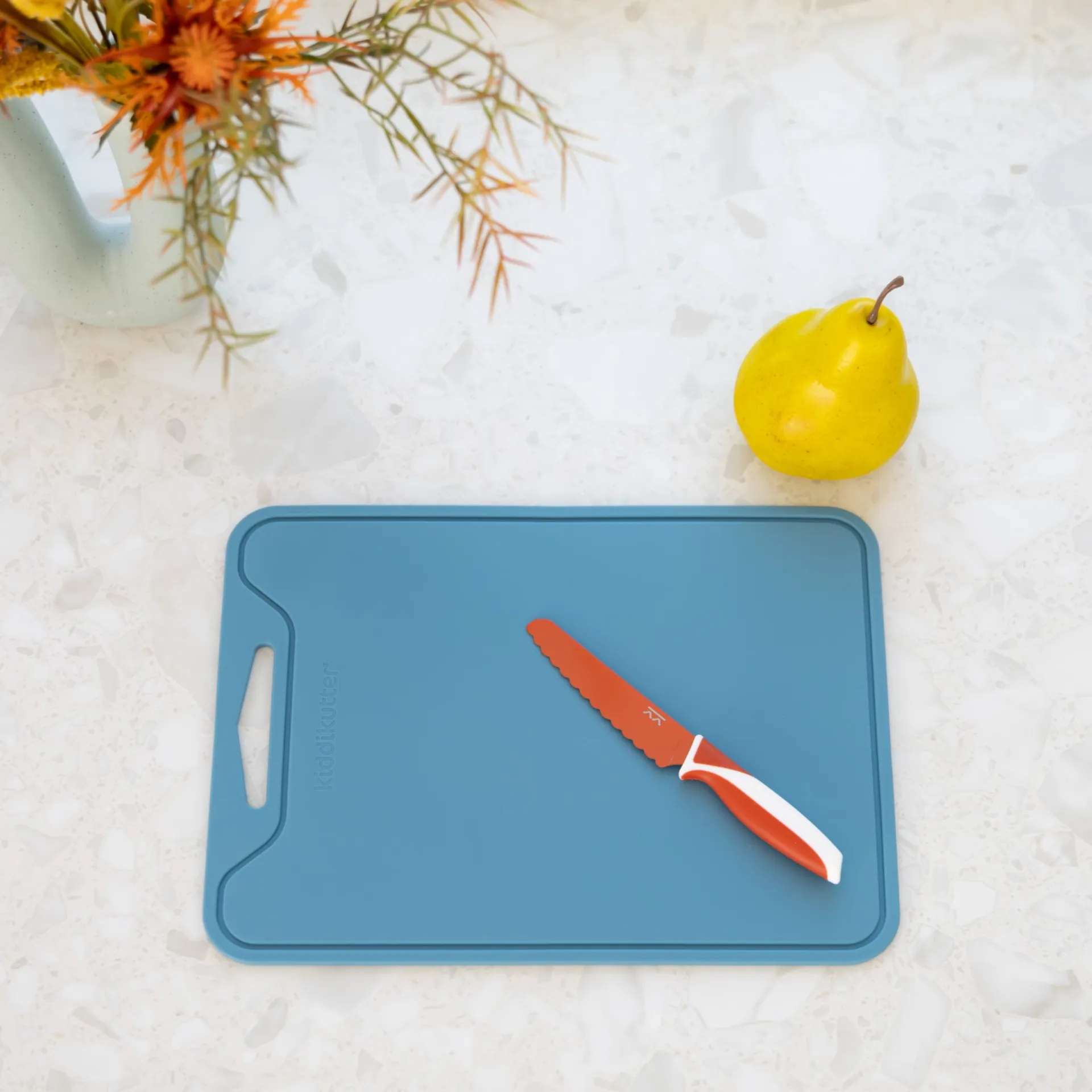 Blue silicone cutting board with a red KiddiKutter knife