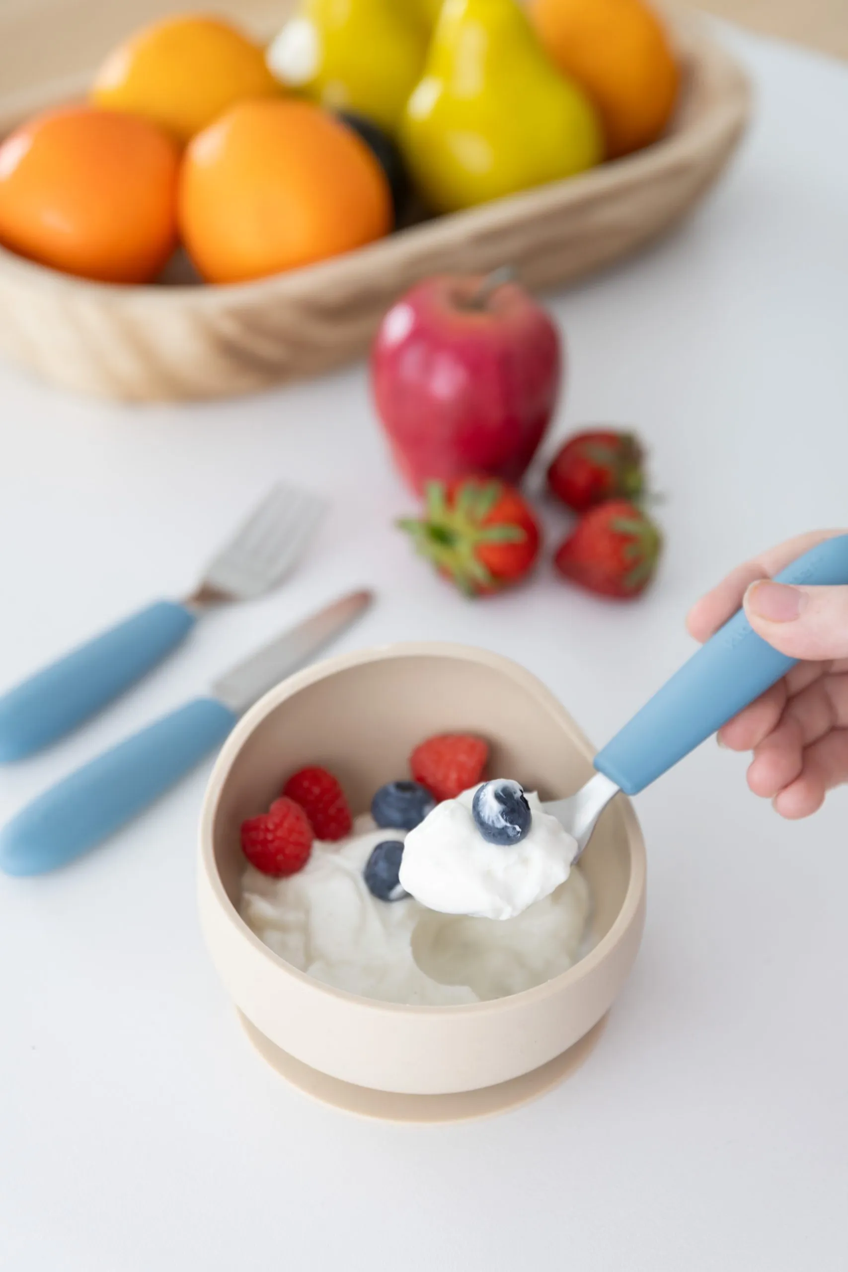 Kids cutlery with a bowl of yoghurt and berries