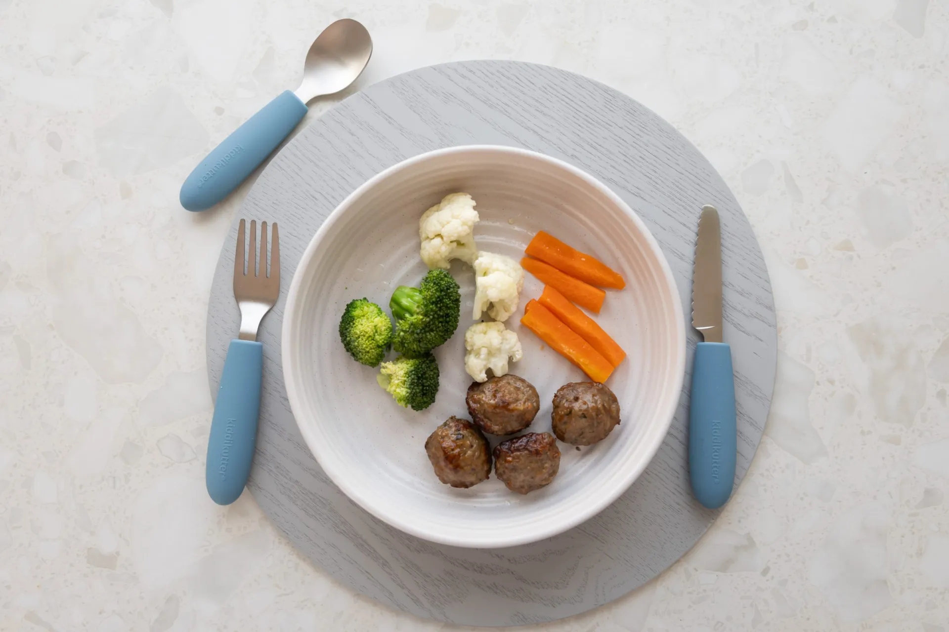 Blue kids cutlery with meatballs and vegetables