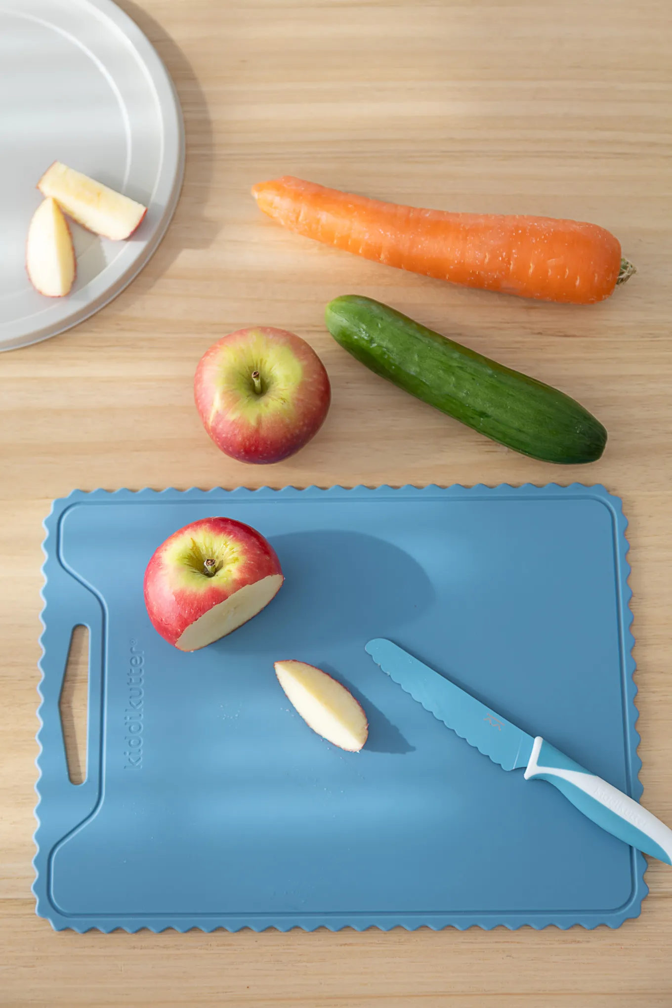 Blue silicone cutting board with an apple and cucumber