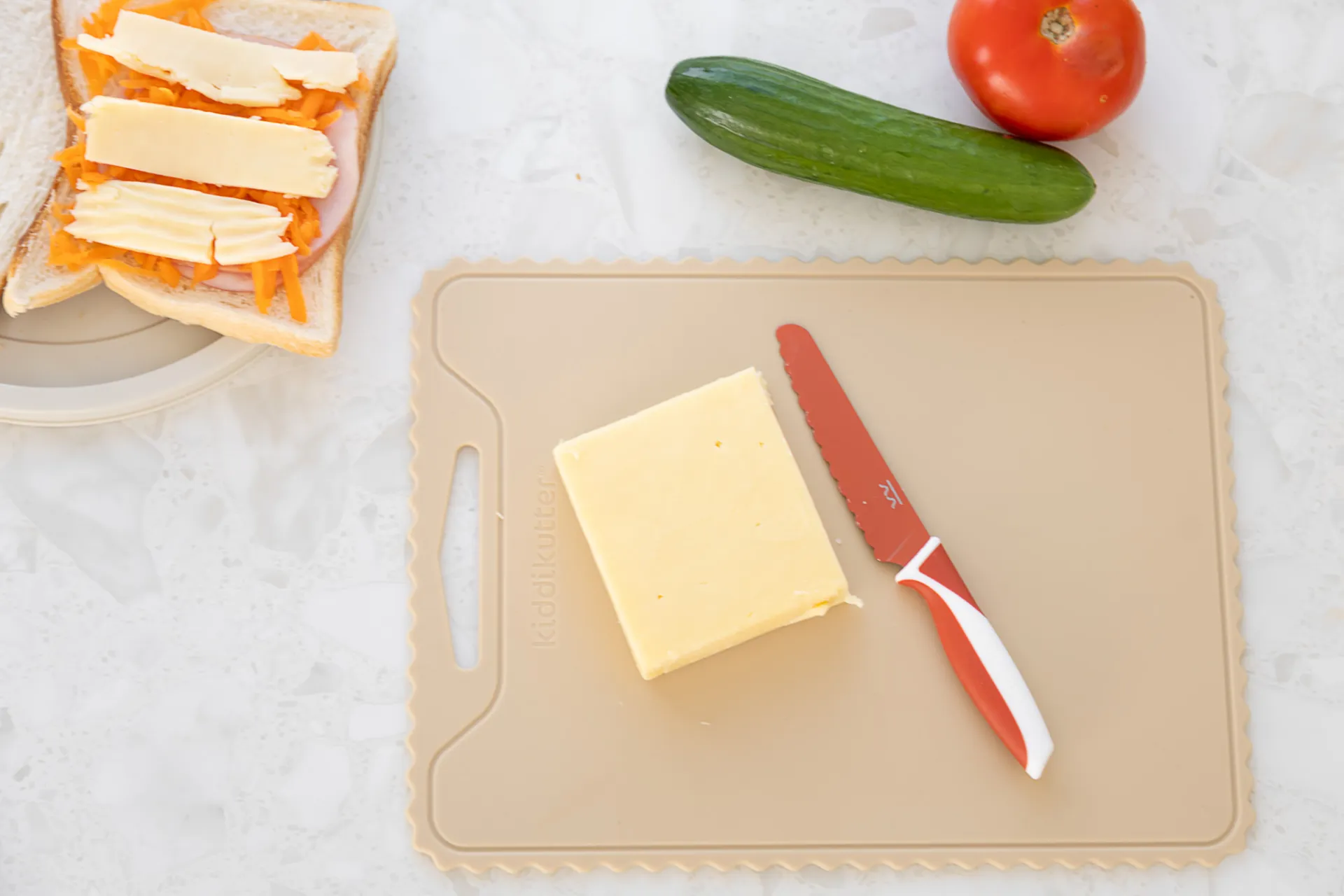 Cream silicone cutting board with cheese and a KiddiKutter