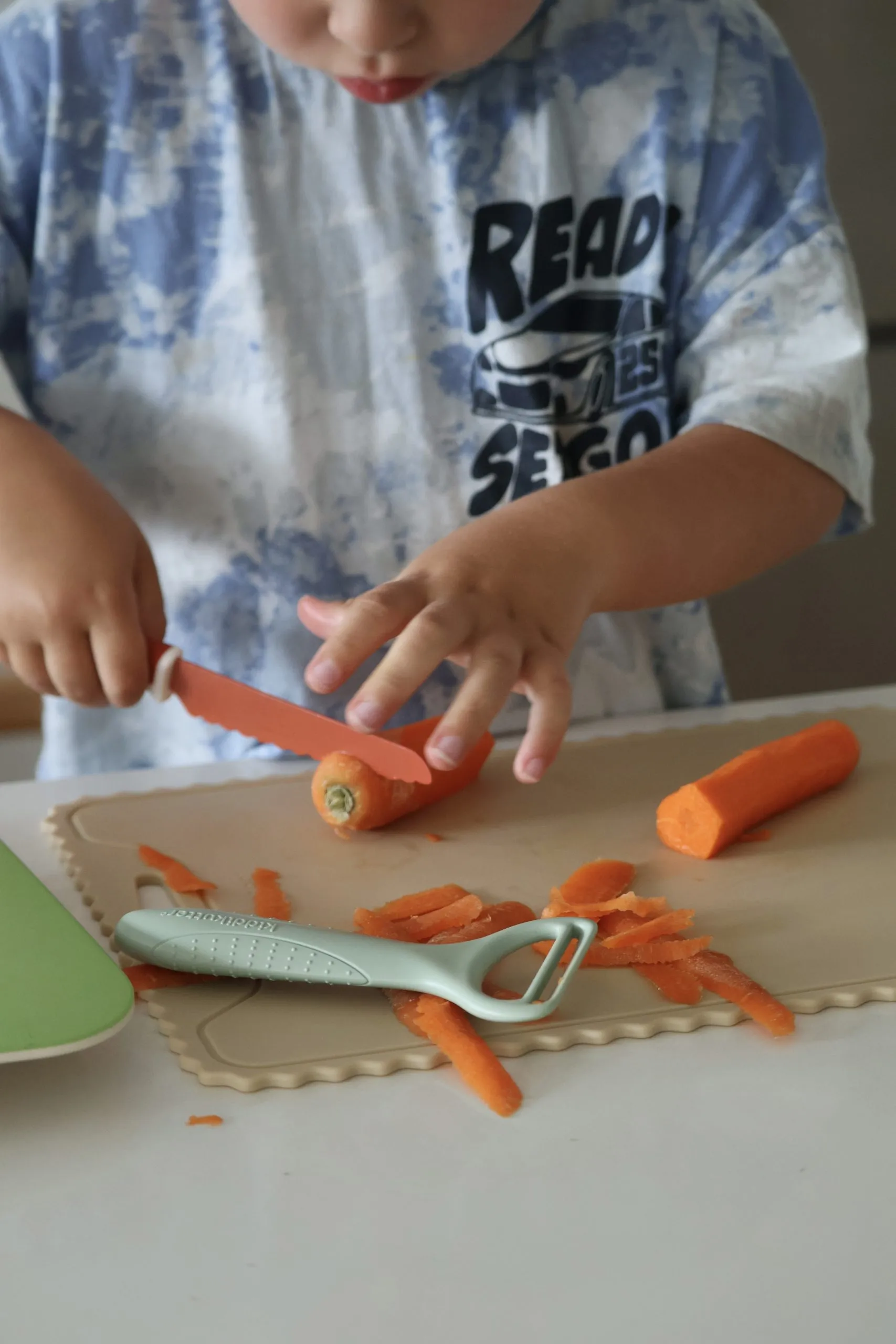Child peeling a carrot with the KiddiKutter Safer Peeler