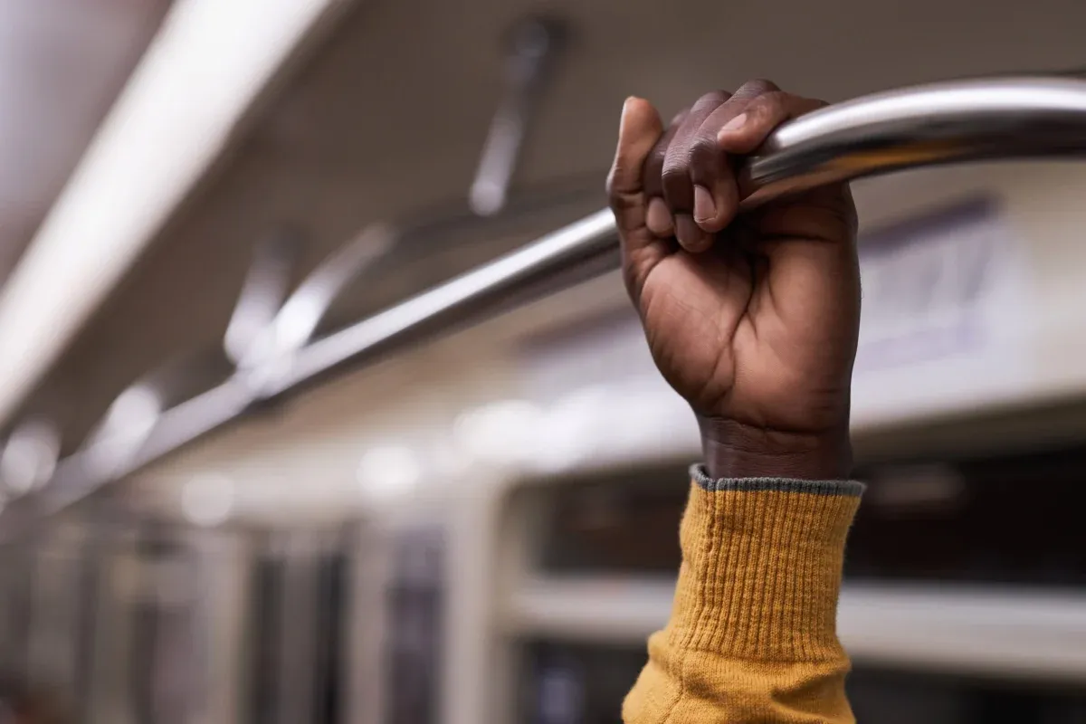 person-holding-metal-bar-on-public-transportation