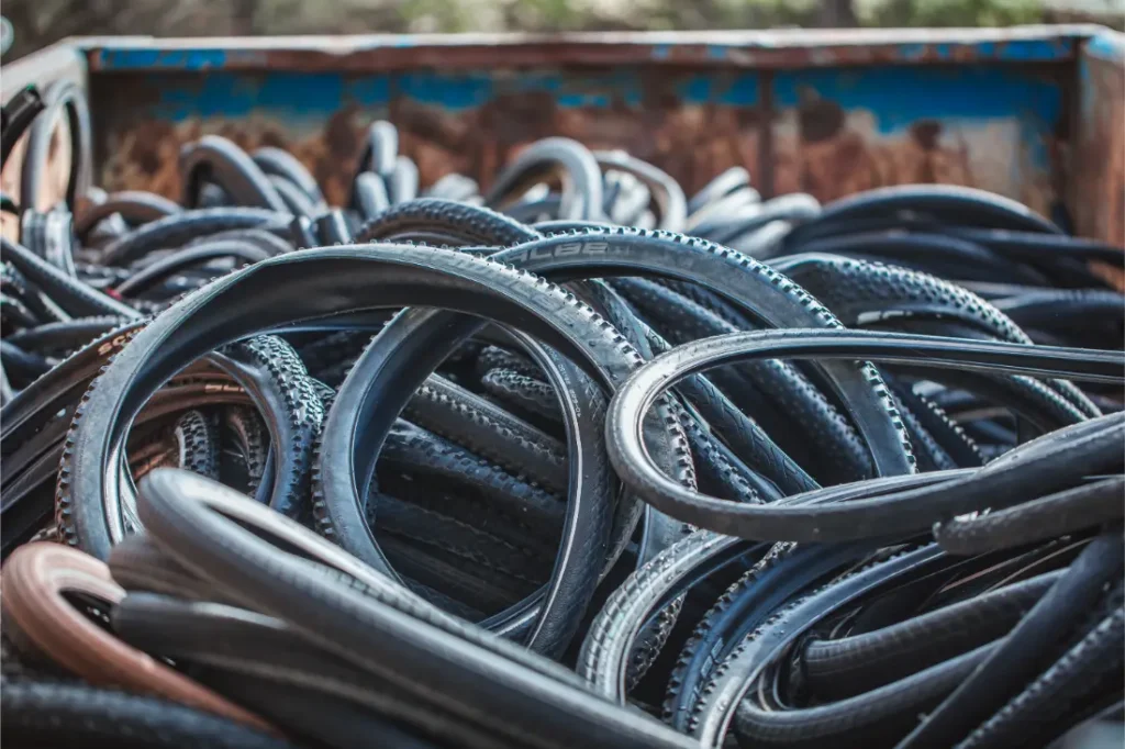 Una pila de neumáticos Schwalbe usados apilados dentro de un contenedor de metal oxidado.