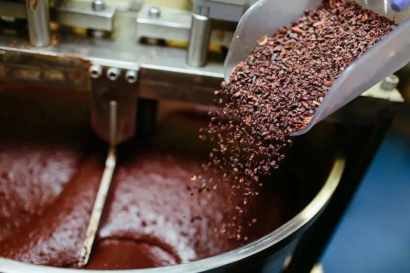 Adding cacao nibs to a melanger / stone grinder / conche