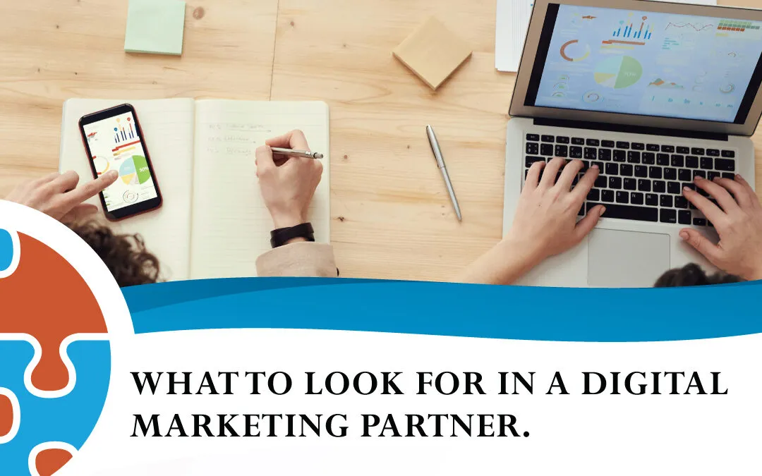 Two people work at a desk with a laptop, smartphone, and notebook. Text on image reads: "A guide for small business: What to look for in a digital marketing partner.