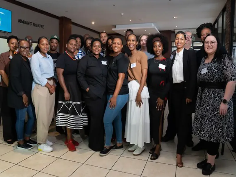 A group of approximately 20 diverse people stands together indoors for a photo at the #BAKING THEATRE during an SMME financial foresight workshop in South Africa. - Proudly Developing