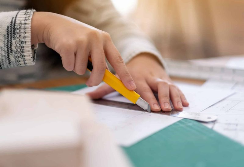 An architect working and cutting papers in office