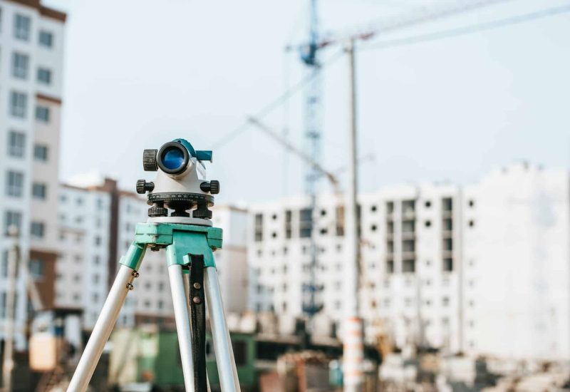 Digital level on tripod with construction site on background