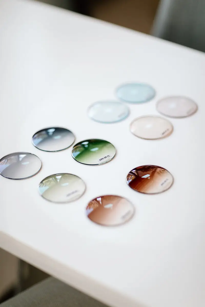 Colorful oval gradient sunglass lenses arranged on a white table.