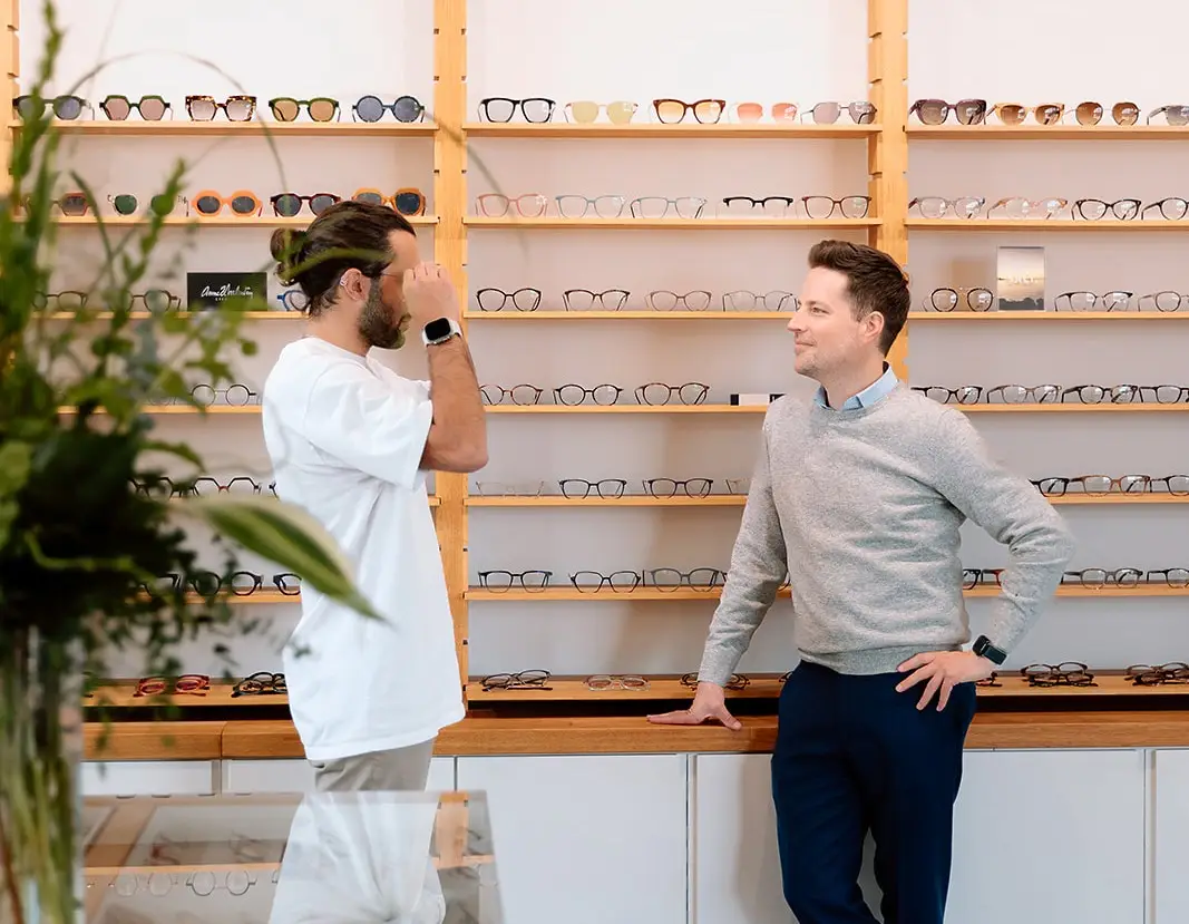Customer tries glasses with help from a sales associate in a bright optical store.