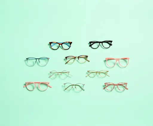 Eyewear for Creatives: Show Off Your Style 1 A collection of nine different trendy eyeglass frames, including tortoise shell, pink, and gold round styles, displayed on a mint green background.