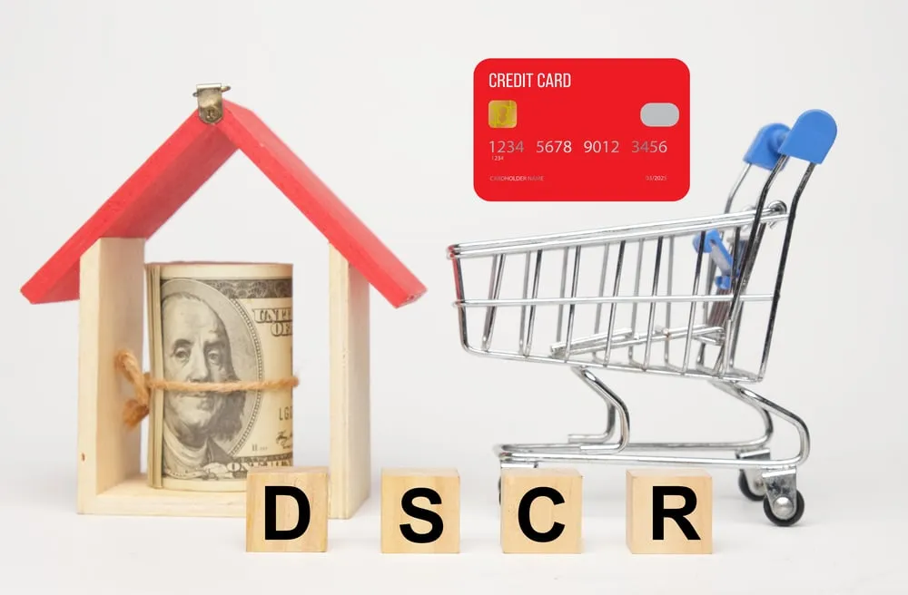 A picture of wooden block with the DSCR letter, cart, credit card illustration, wooden house and fake money.