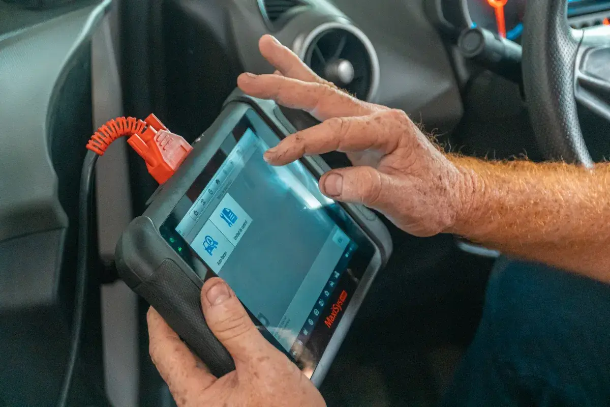 Mechanic using a diagnostic tool inside a car to check for engine issues and ensure proper maintenance