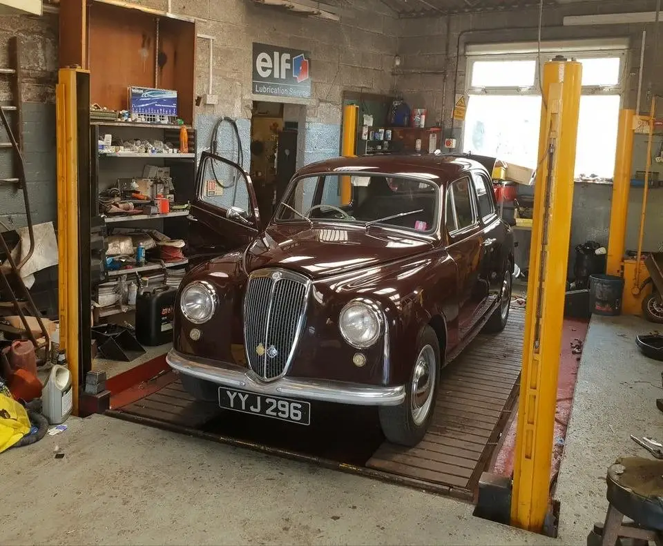 Car raised on a two-post lift in a repair shop, the setup needed to reach a rear main seal