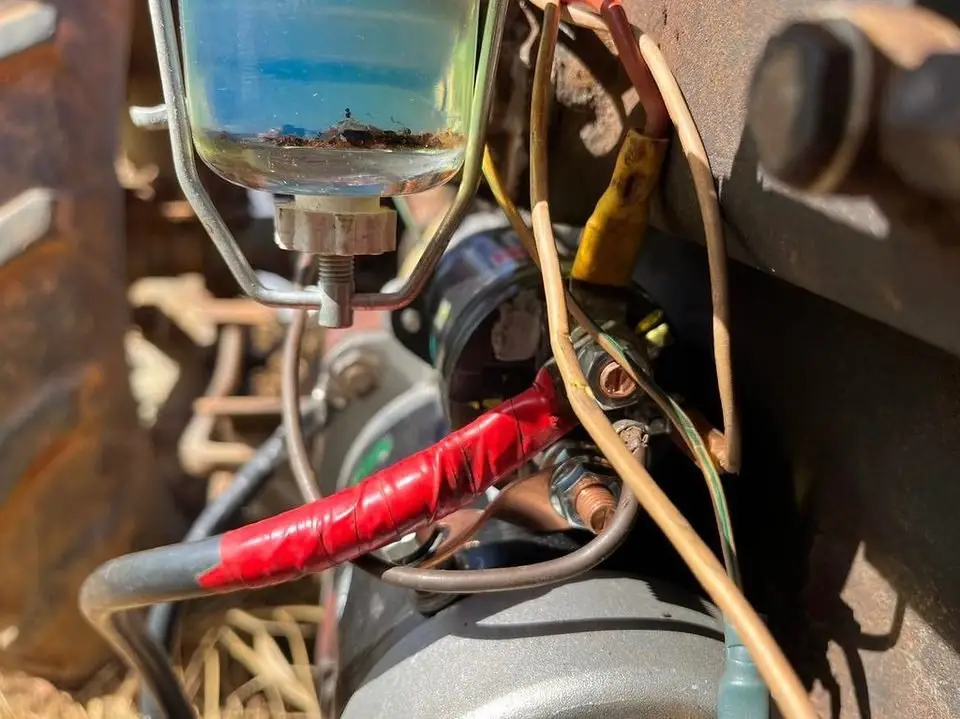 Heavy red battery cable running to the starter motor in an older engine bay