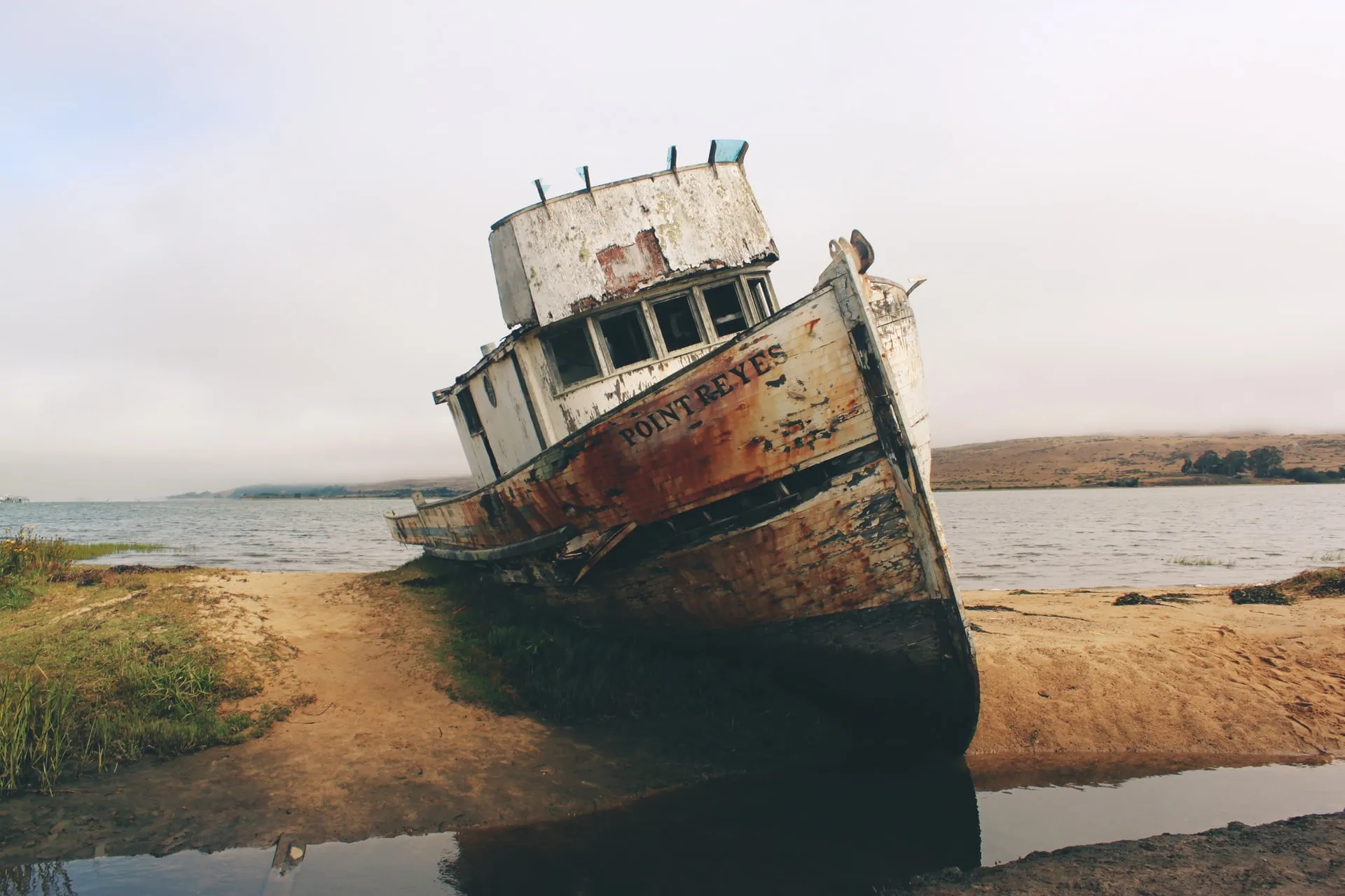 Auf eine Sandbank aufgelaufenes, verwittertes Schiff.