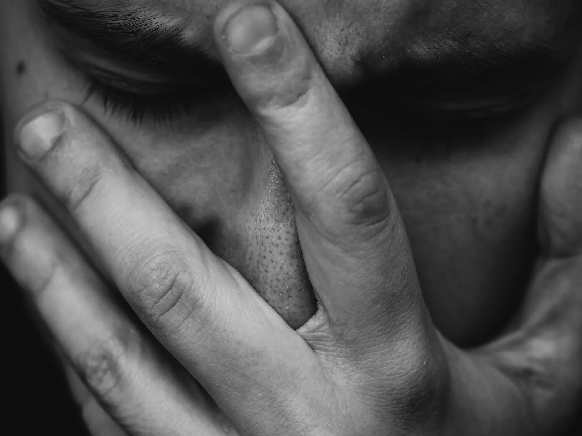 Großaufnahme eines Mannes der entsetzt die Hand vor das Gesicht hält als Ausdruck von Suizid-Gedanken