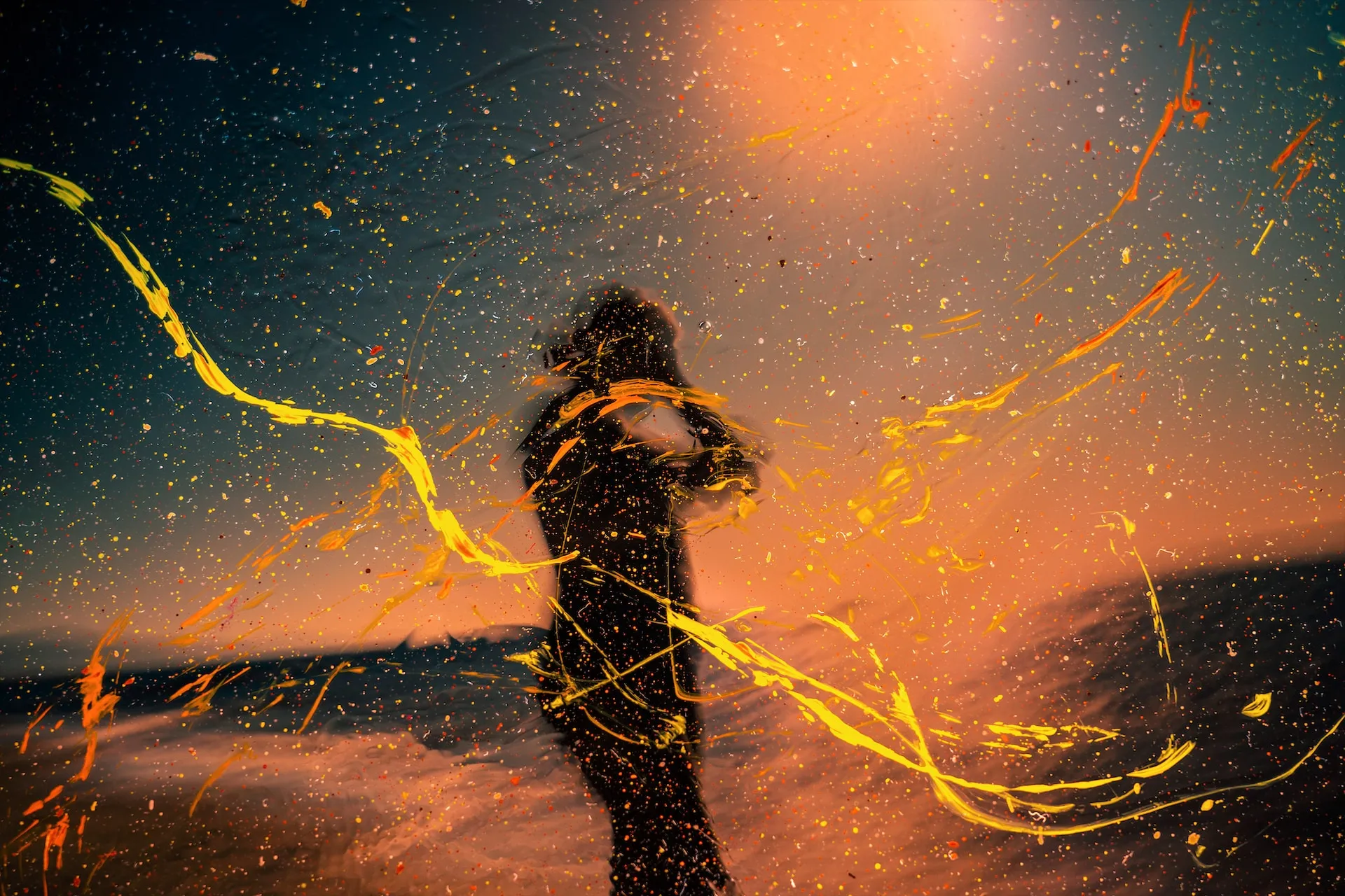 Silhouette einer Person, die bei Sonnenuntergang im Freien steht, überlagert von dynamischen gelben und orangefarbenen Farbspritzern und Schlieren, die die lebendigen Einsichten der systemischen beratung symbolisieren.