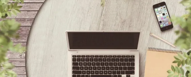 laptop on the table with notebook and flowers