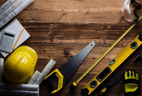 Construction tools including a hard hat, saw, level, and tape measure laid out by a general contractor in Orlando, FL.