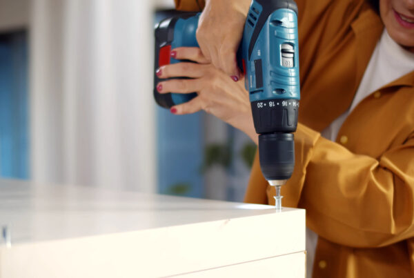 Woman using a power drill to install a closet shelf, performing precise repair and installation work.