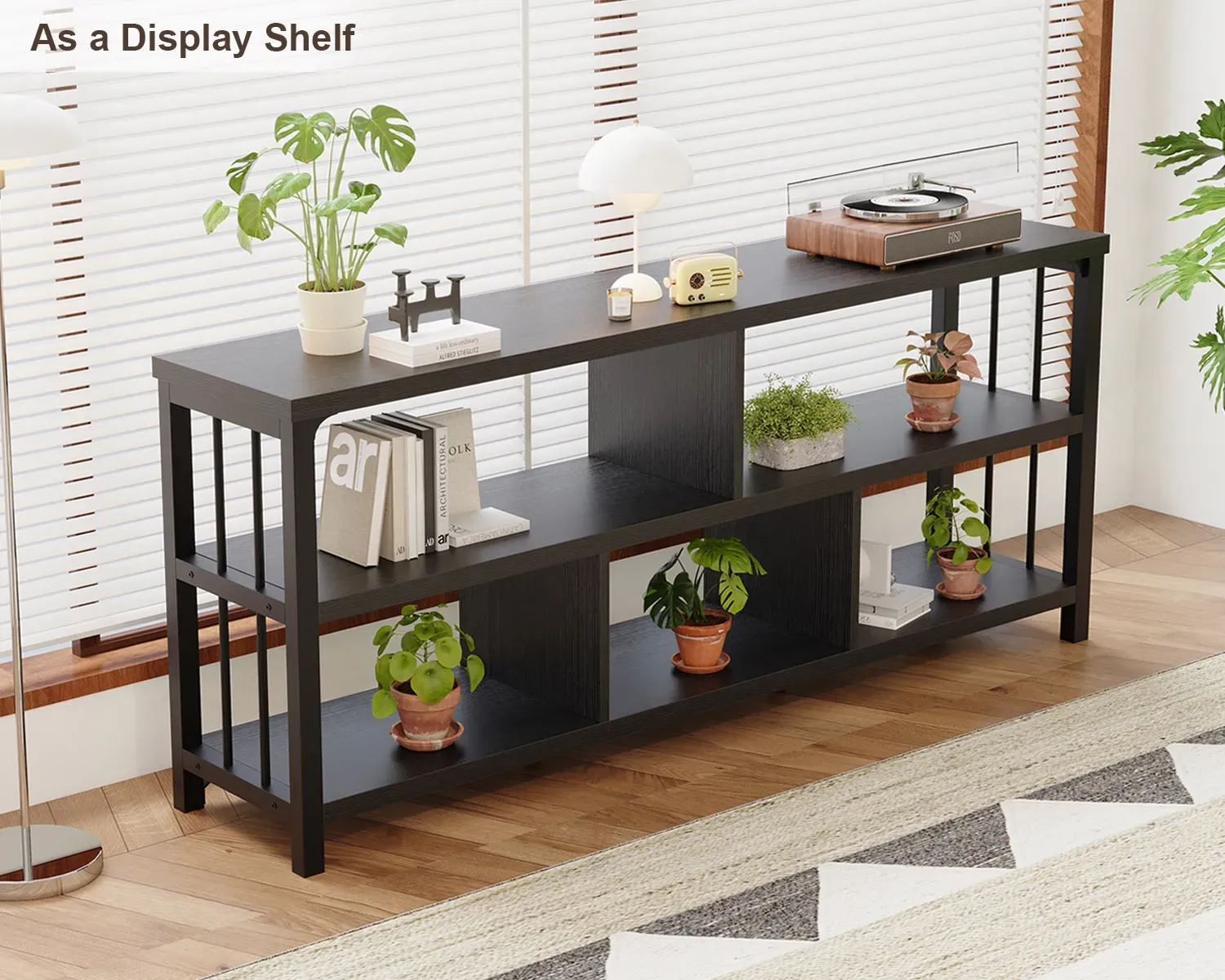 Lo scaffale espositivo nero 7_结果 contiene libri, piante in vaso, decorazioni, una lampada, e un giradischi OEM in una stanza soleggiata con pavimenti in legno e grandi finestre.