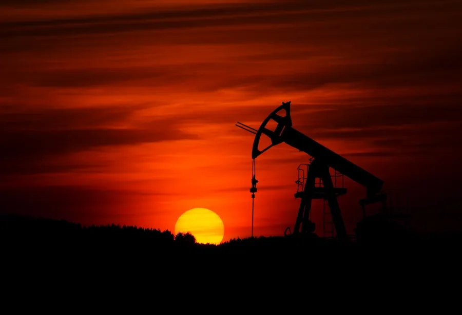 Silhouette of an oil pumpjack against a vibrant orange sunset sky, basking in the glow much like custom magnetic drive pump solutions that elevate innovation with precision and efficiency.