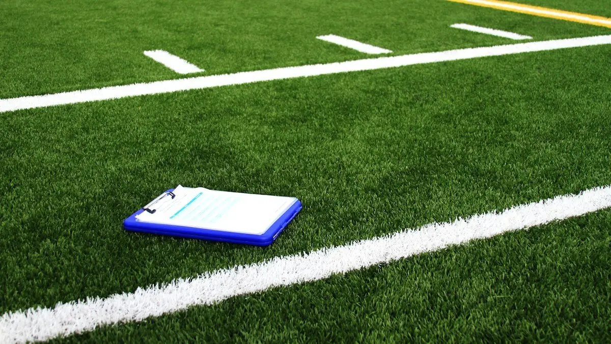 Clipboard resting on green turf beside the yard lines of a football field