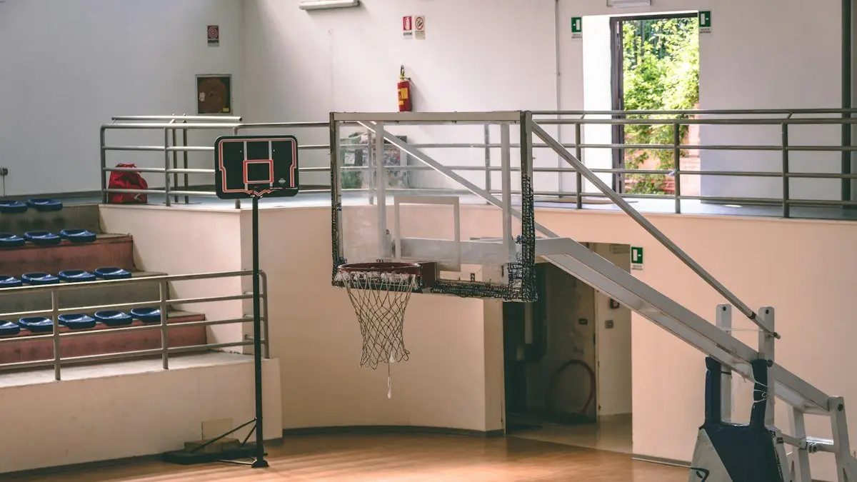 Indoor basketball court with a portable hoop and empty bleachers