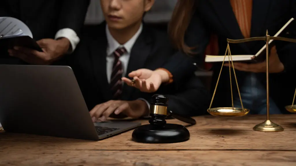 someone working on laptop beside judge gavel and scales