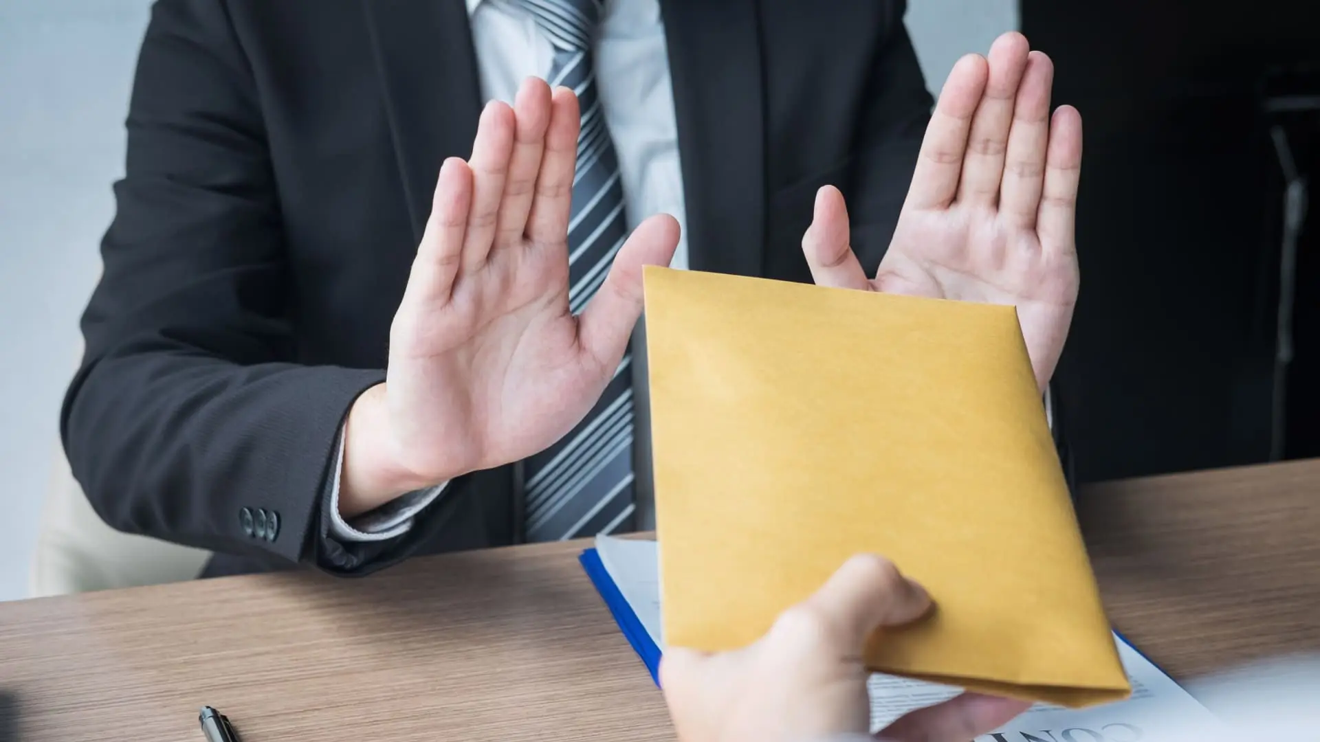 87 Businessman refusing an envelope offered during a meeting.