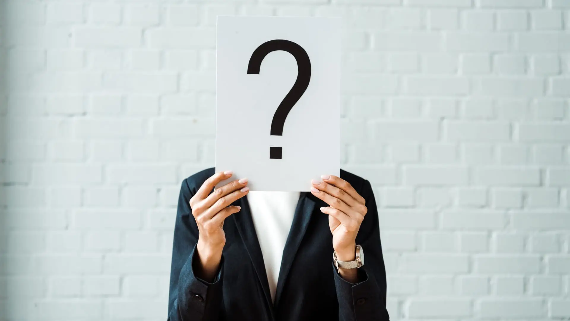 Person holding a question mark sign in front of their face