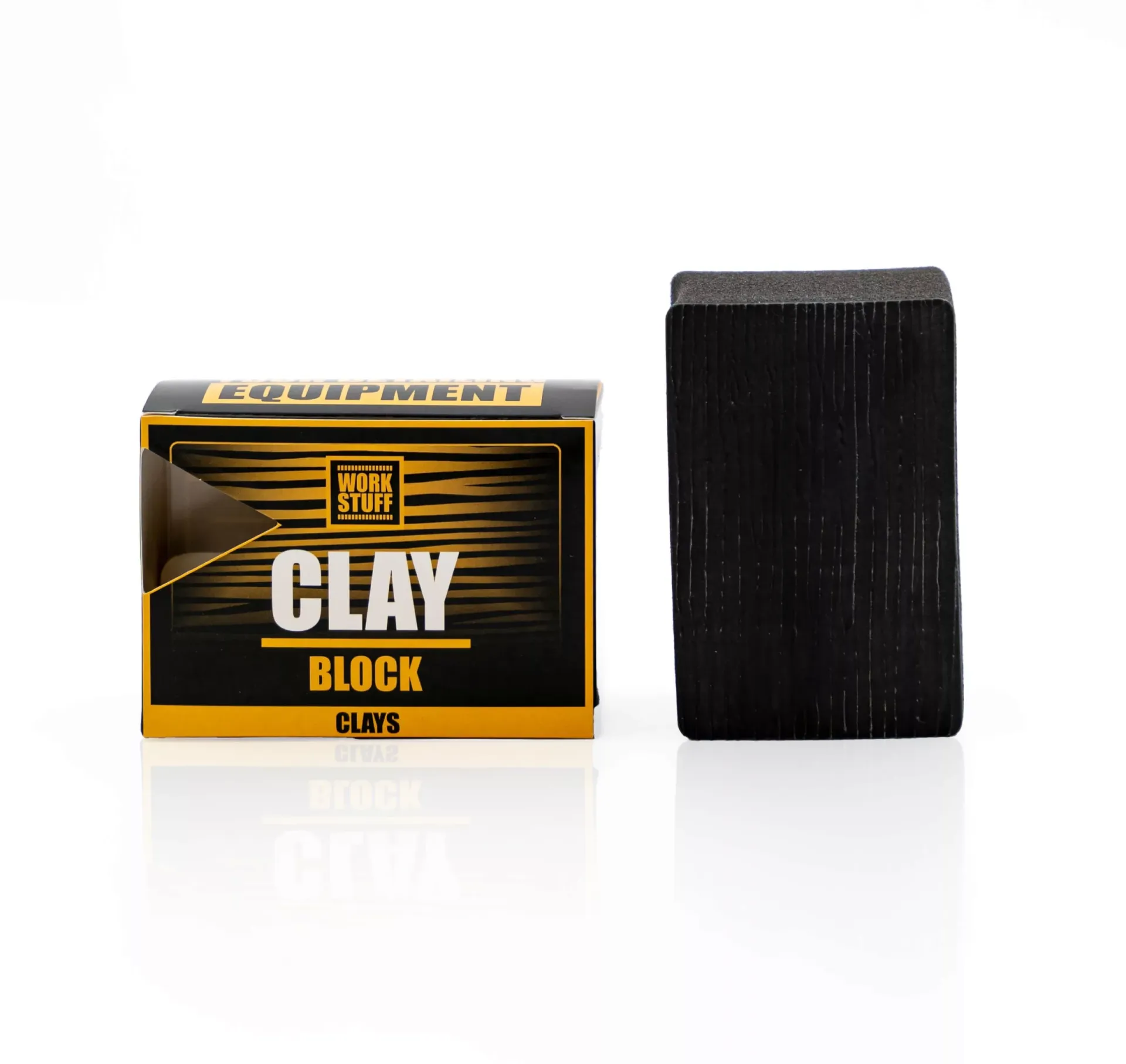 Prostokątna czarna glinka stoi pionowo obok opakowania z etykietą Work Stuff Clay Block w kolorach czarnym, białym i żółtym.