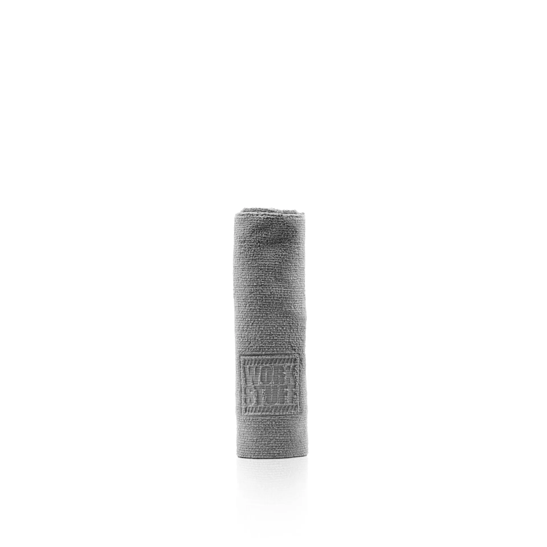 Toalla gris enrollada con un dibujo rectangular en relieve, de pie sobre un fondo blanco sutilmente texturizado.