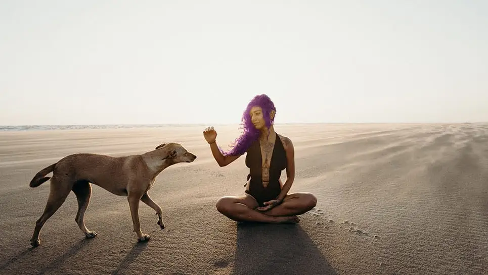Une fille aux cheveux violet avec son chien à la plage
