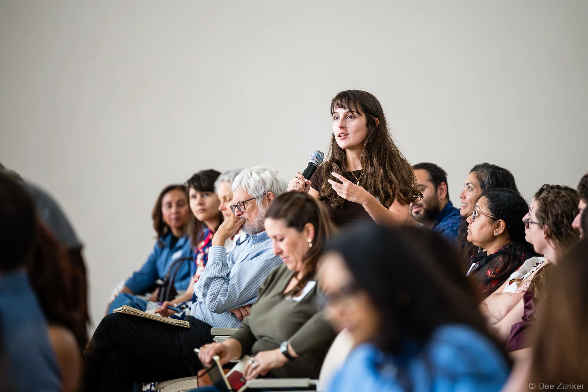 Attendee stands holding a microphone to ask a question during the Gulf Coast Green 2026 conference at The Ismaili Center, Houston.