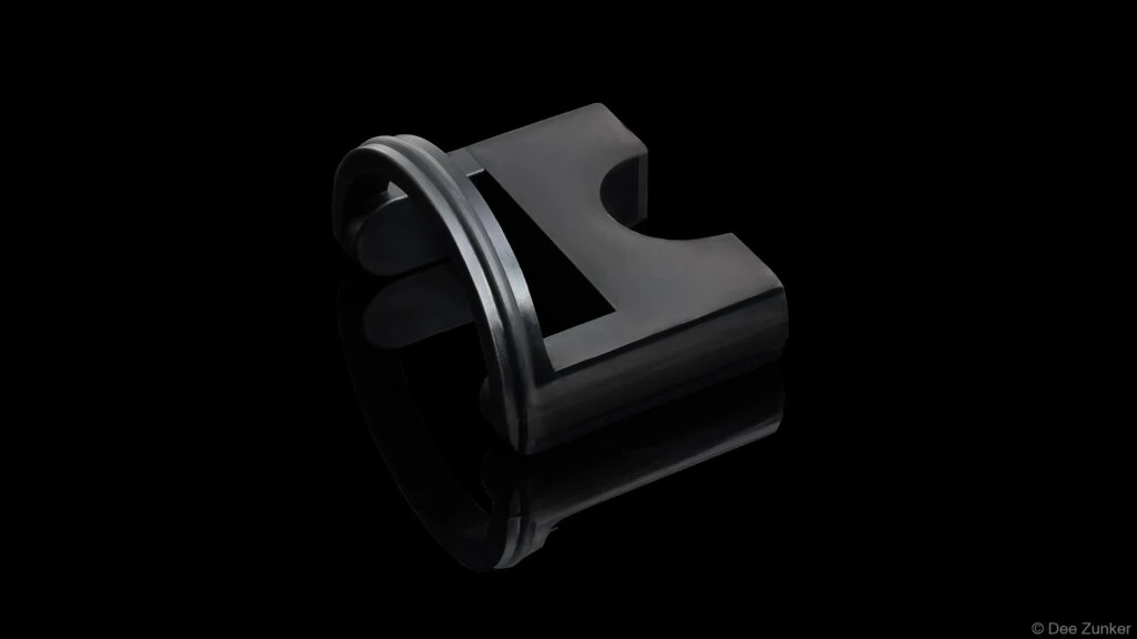 Black anodized industrial drilling tool component with O-ring seal, shot on reflective black background, Houston product photography.