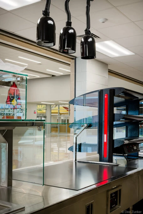 Stainless steel cafeteria serving counter with heat lamps and pizza warmer at a Houston junior high school cafeteria.