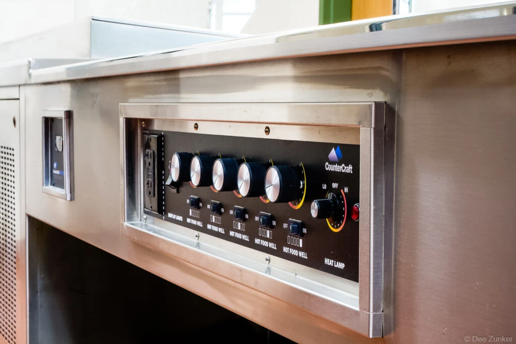 CounterCraft stainless steel food service counter control panel with hot food well knobs and heat lamp dial, Houston commercial product photography.