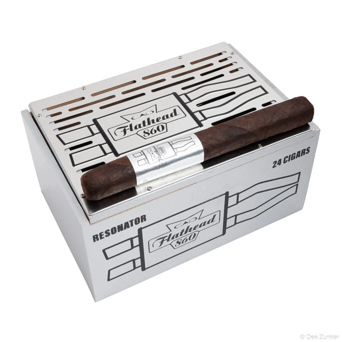 CAO Flathead 860 Resonator cigar box containing 24 cigars with one cigar displayed on top, white background product photography.