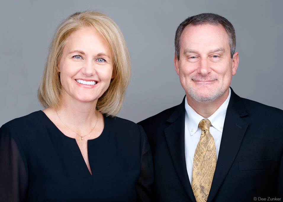 Male and female Houston attorneys in dark business attire pose together for professional corporate headshots against a gray studio background.