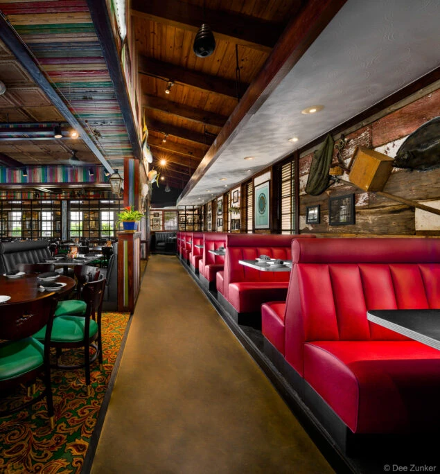 Red leather booths line a rustic seafood restaurant dining room in Katy TX featuring wood beam ceilings and eclectic nautical decor.