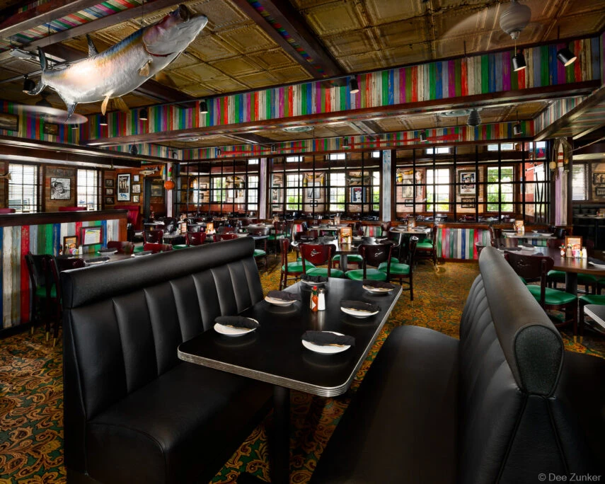 Colorful striped wood-panel walls, black leather booths, and mounted fish sculpture inside Babins Seafood restaurant in Katy, TX.