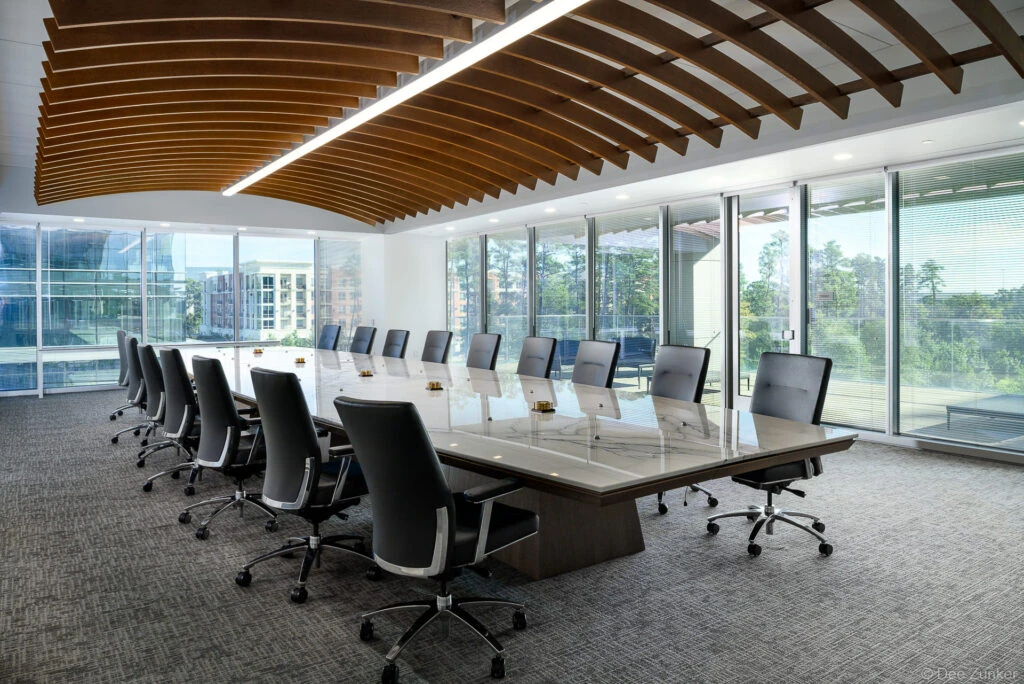 Executive conference room with dramatic ship keel wood ceiling, marble boardroom table, black leather chairs, and floor-to-ceiling windows in Spring, TX